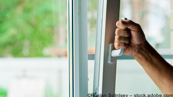 Mann kippt Fenster mit Wärmedämmung